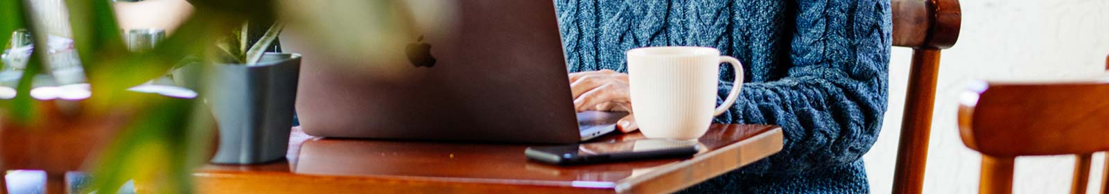 Person sitting at kitchen table, working on laptop