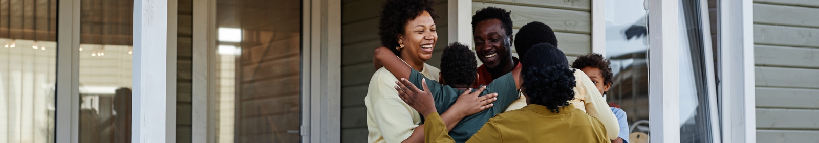 a large family group hug outside in front of a house